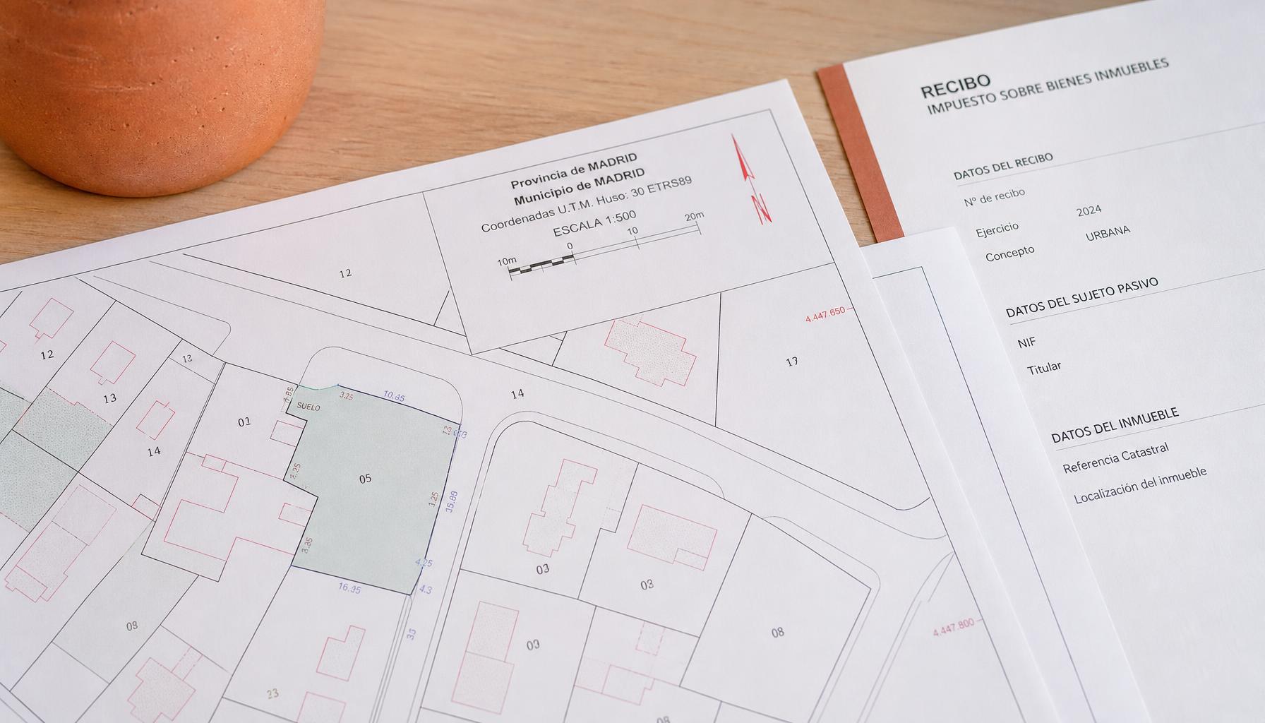 Plano catastral y recibo del IBI sobre una mesa de madera clara